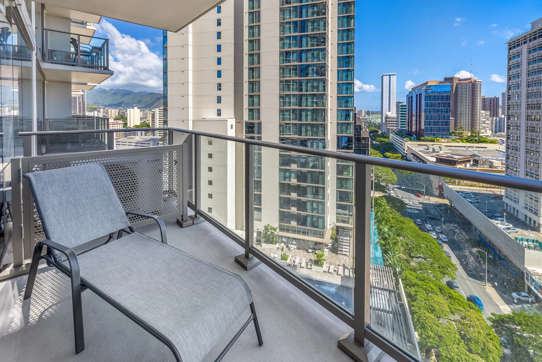 A balcony with lounge seating overlooks nearby high-rise buildings.