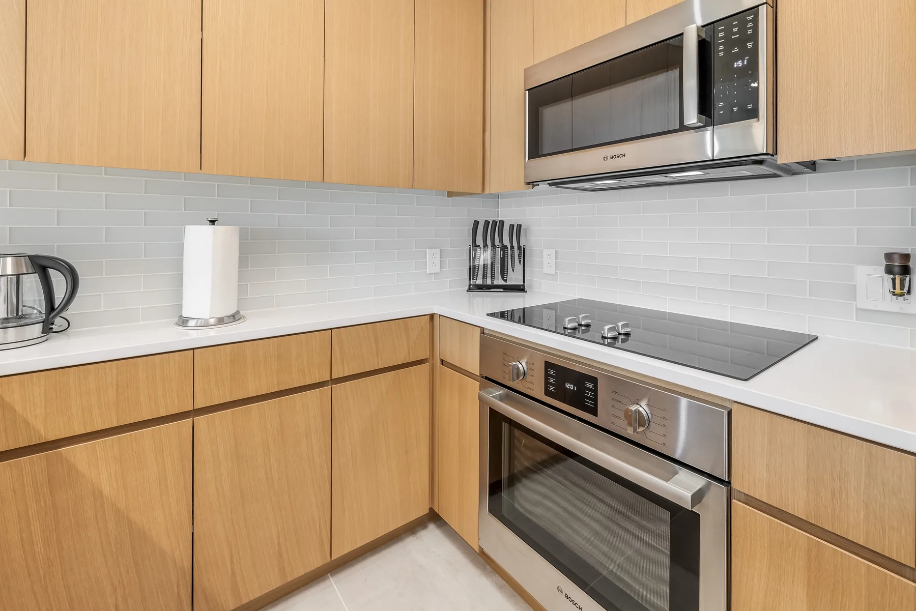 A modern kitchen with wooden cabinets, a cooktop, and built-in appliances.