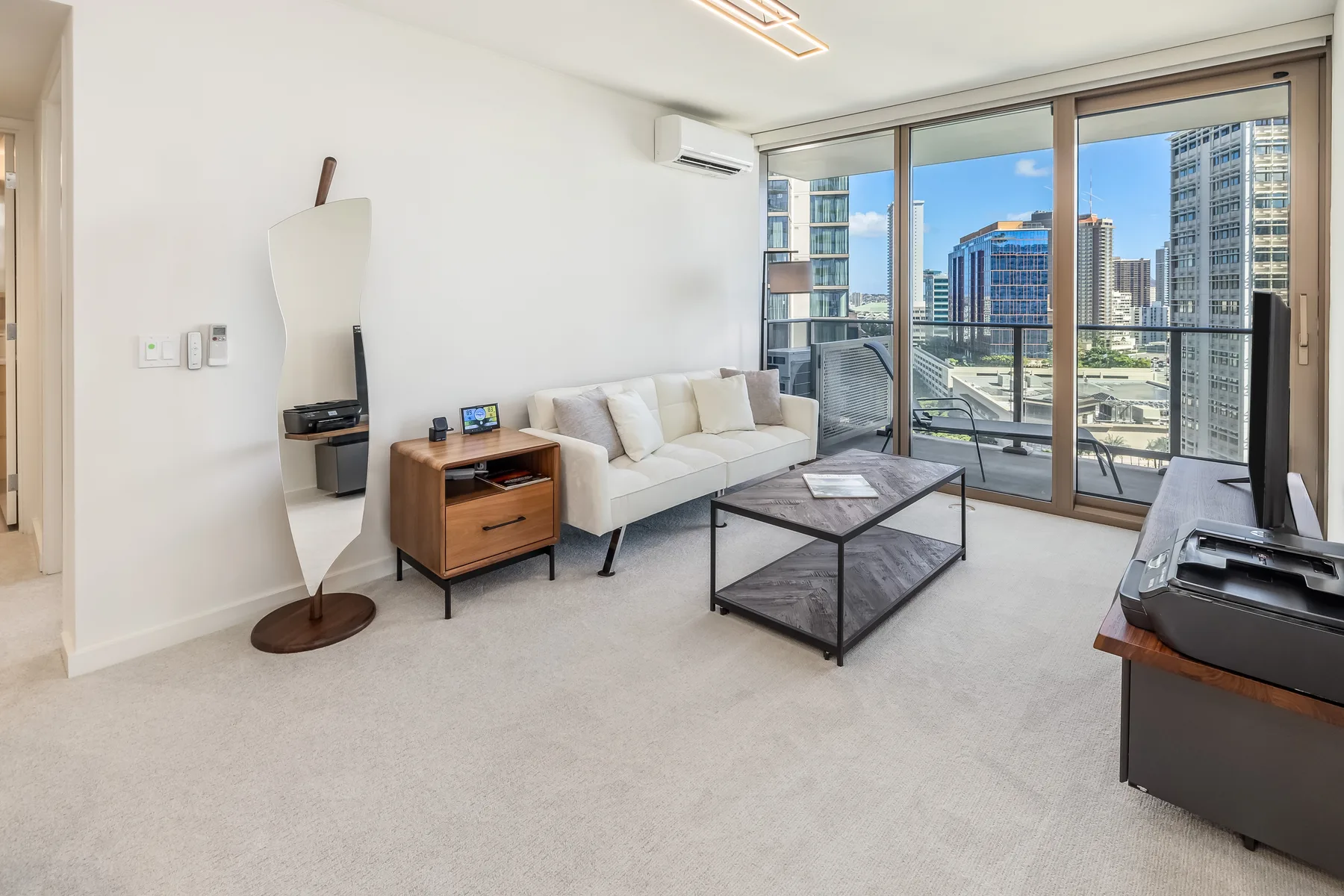 A bright living room with seating and a coffee table beside large windows.