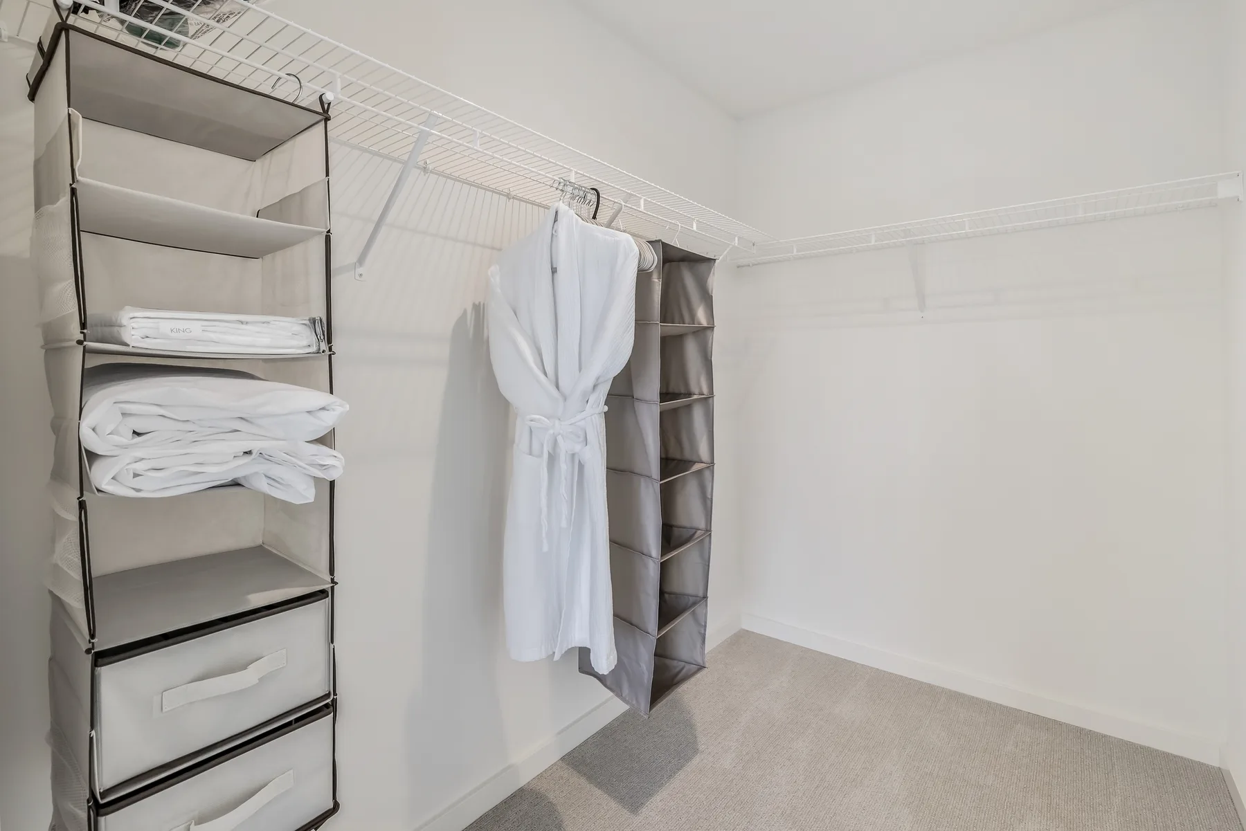 A walk-in closet with open shelving and a white robe hanging on a hook.