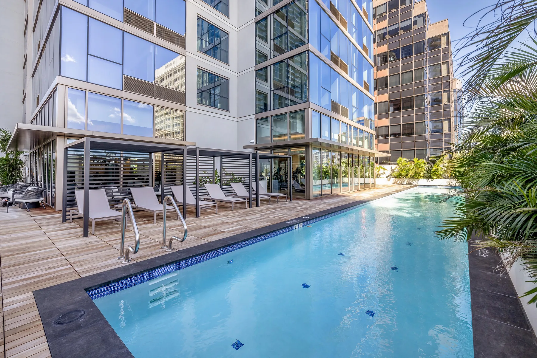 An outdoor swimming pool beside a modern building, with seating along the deck.