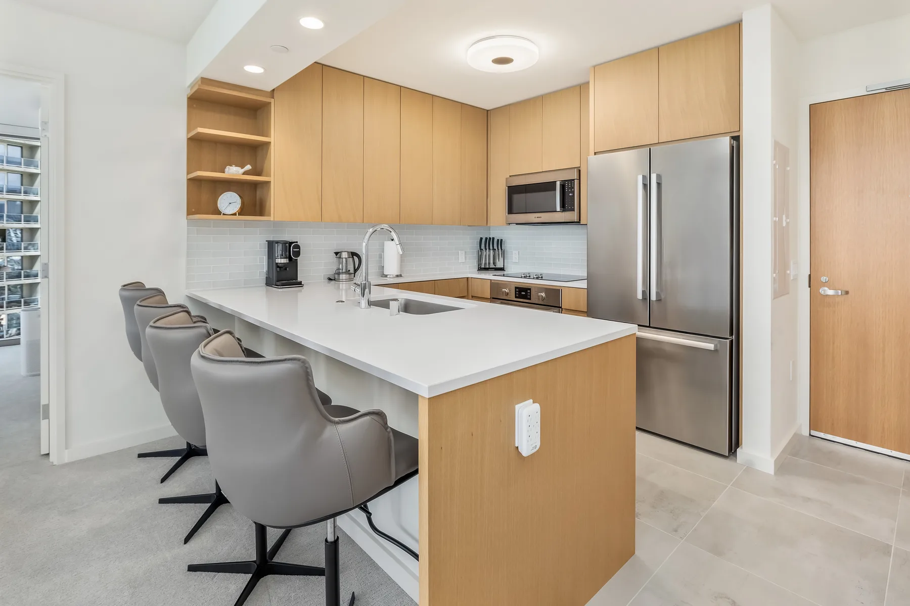 A bright modern kitchen with light wood cabinetry and a large island.
