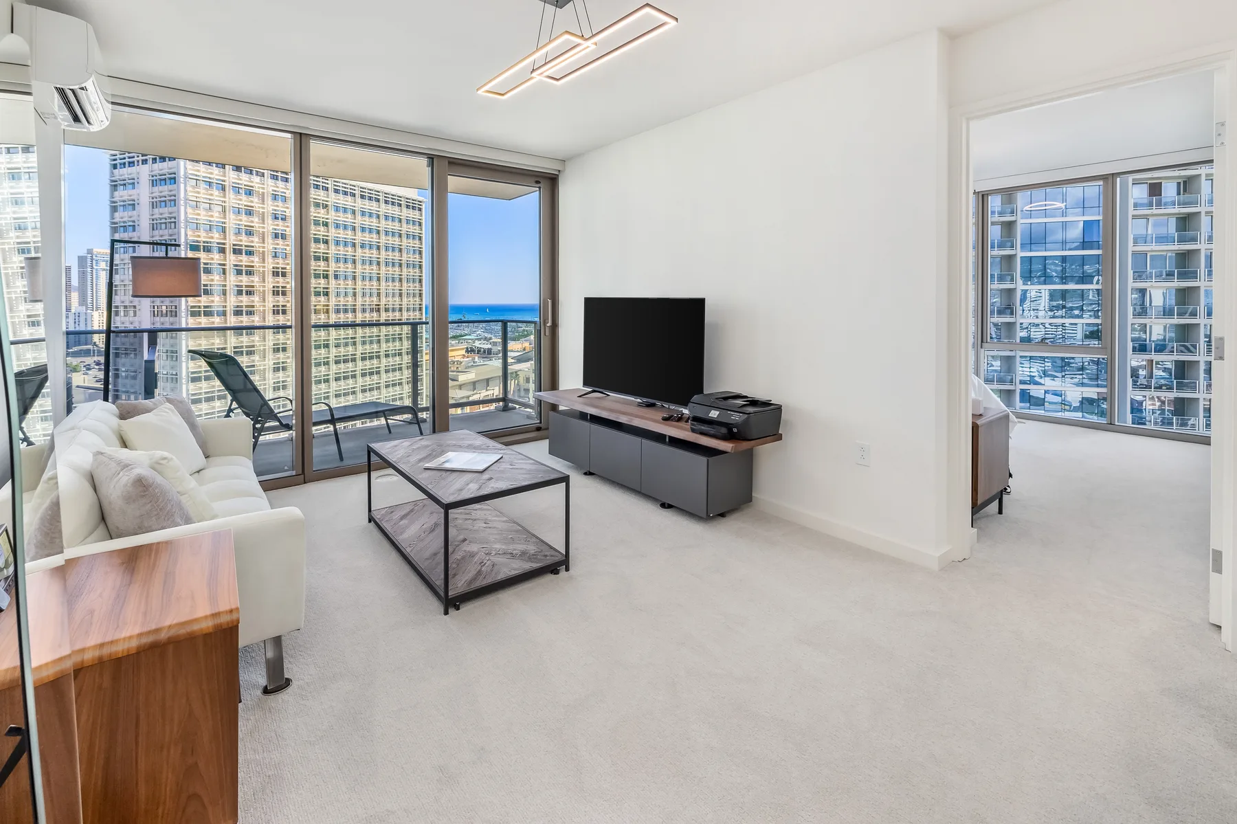 A bright living room with seating, a coffee table, and large windows.
