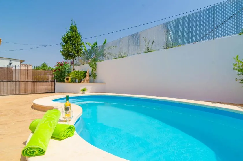 Una piscina al aire libre con agua azul junto a una terraza pavimentada clara.