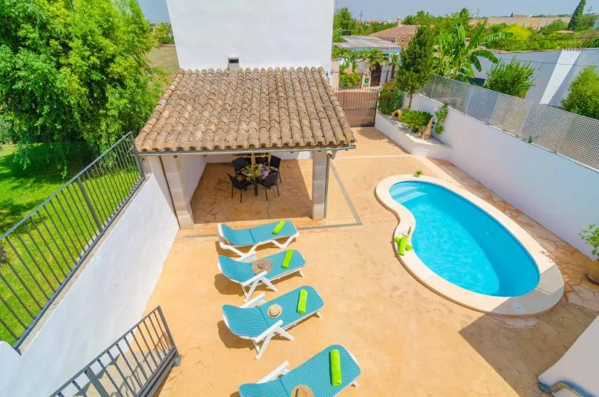 Un patio exterior tiene una pequeña piscina y asientos junto a una zona de comedor cubierta.