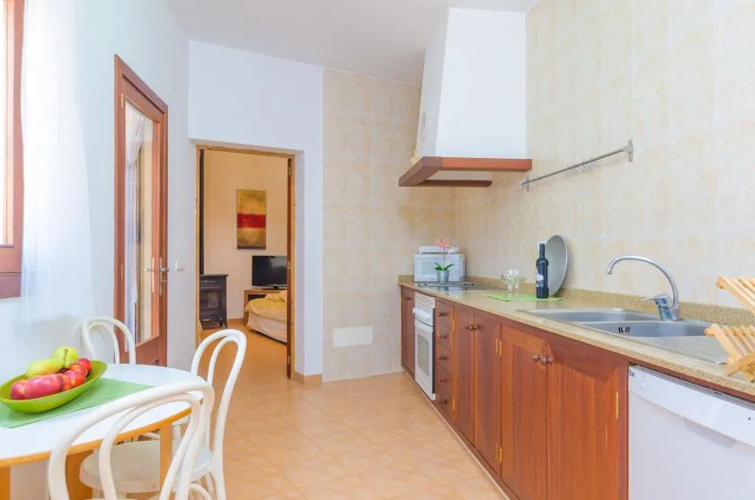 A bright kitchen with wooden cabinets and a small dining table by the window.