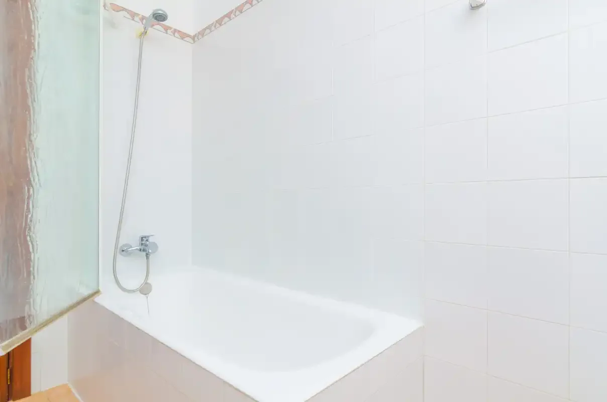 A bathroom with a bathtub and wall-mounted shower.