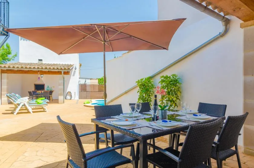 An outdoor dining area with a table and seating beneath a large sun umbrella.