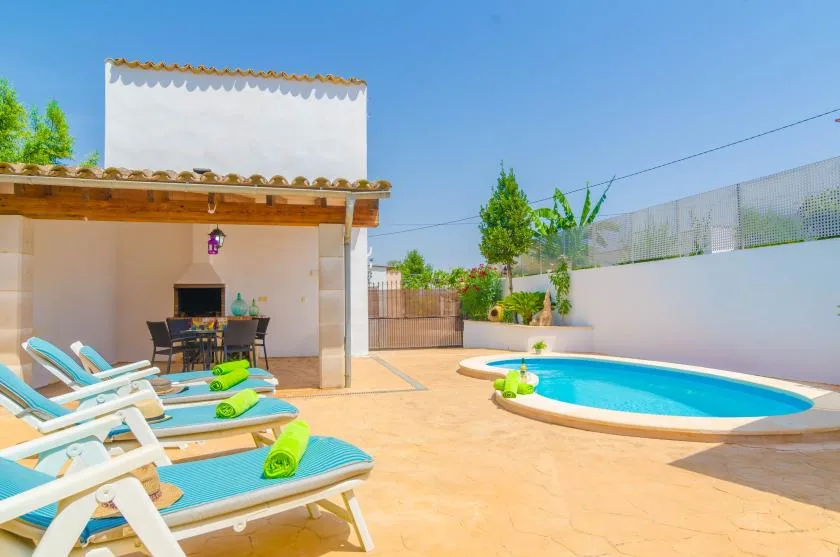 Una zona de piscina al aire libre con tumbonas junto a un patio sombreado.