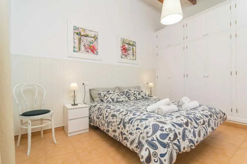 A bedroom with a patterned bedspread and white built-in cabinets.