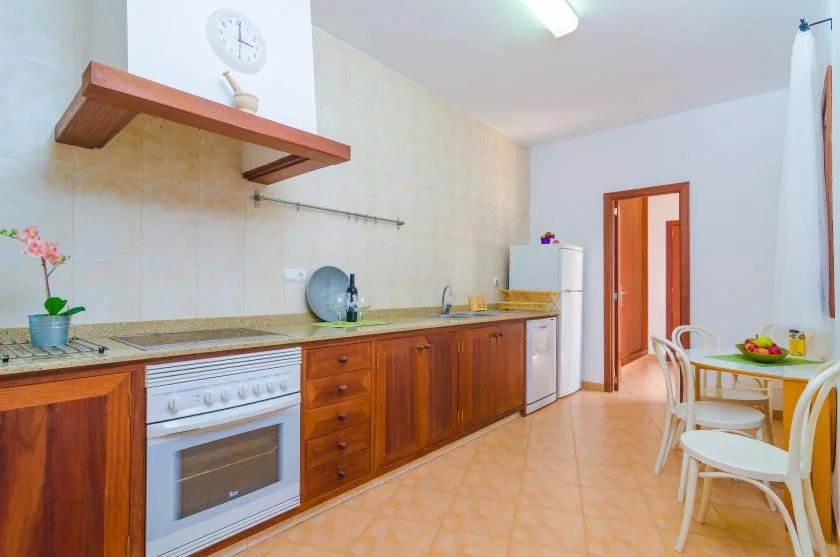 A kitchen with wooden cabinets, a stove, and a dining table.