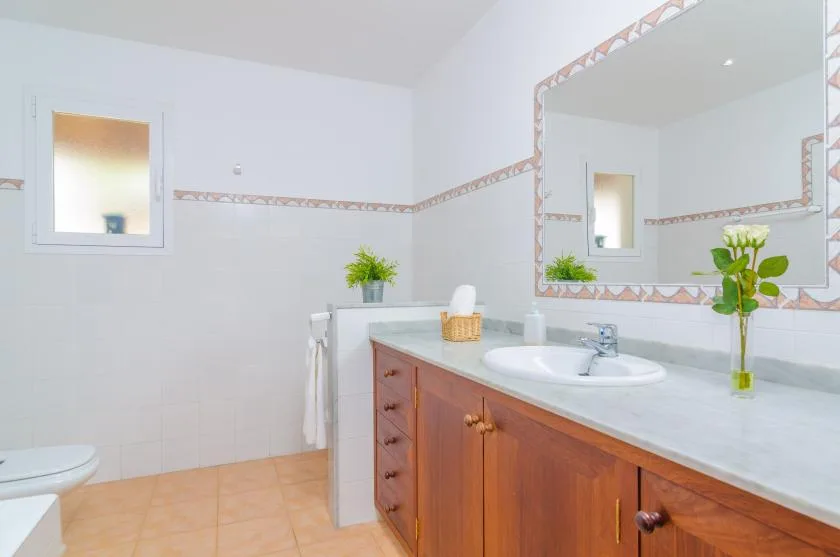 A bright bathroom with a long vanity, sink, and large wall mirror.