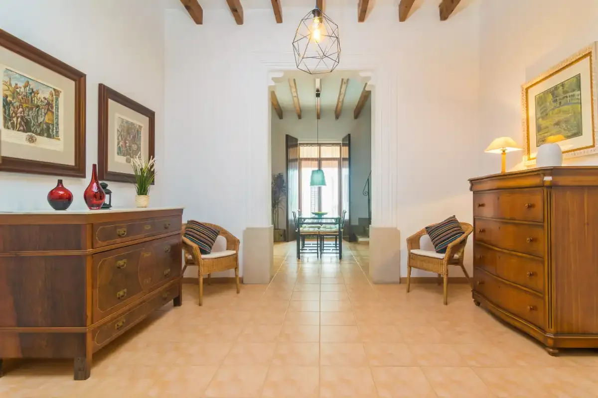 A bright interior room with wooden dressers and seating beside a central doorway.