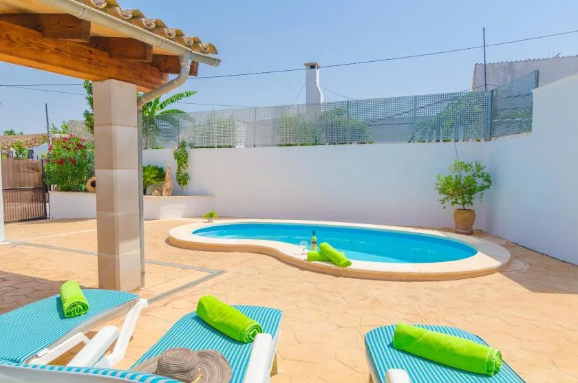 Una piscina al aire libre está junto a un patio pavimentado con tumbonas.