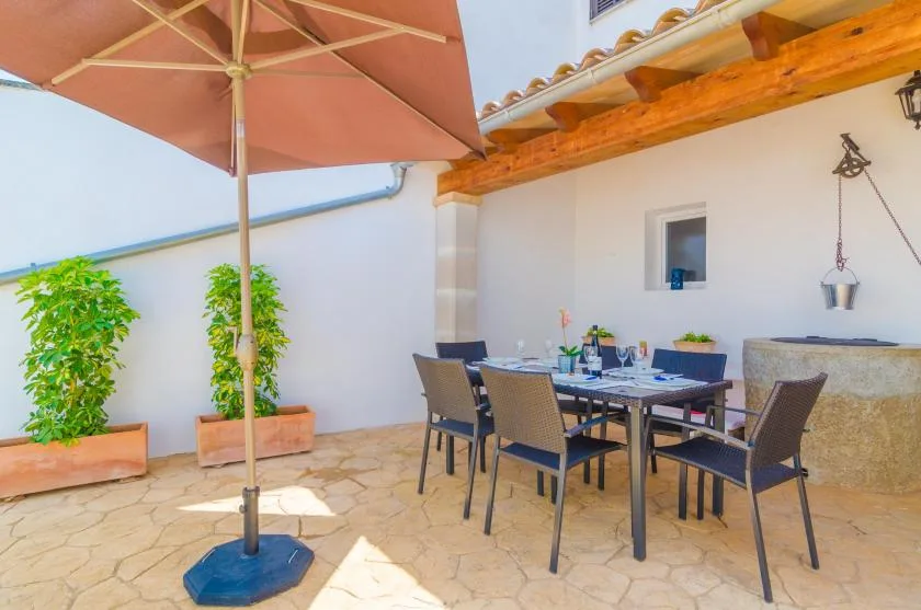 An outdoor dining patio with a table and chairs beneath a large umbrella.
