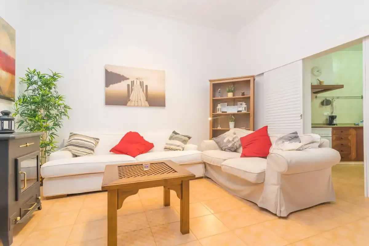 A bright living room with pale seating, a wooden coffee table, and a plant.