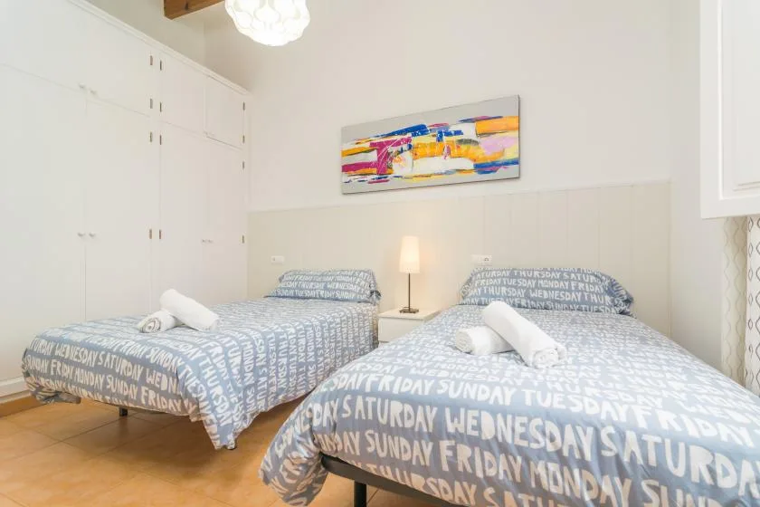 A bright bedroom with two beds dressed in blue-and-white patterned bedding.