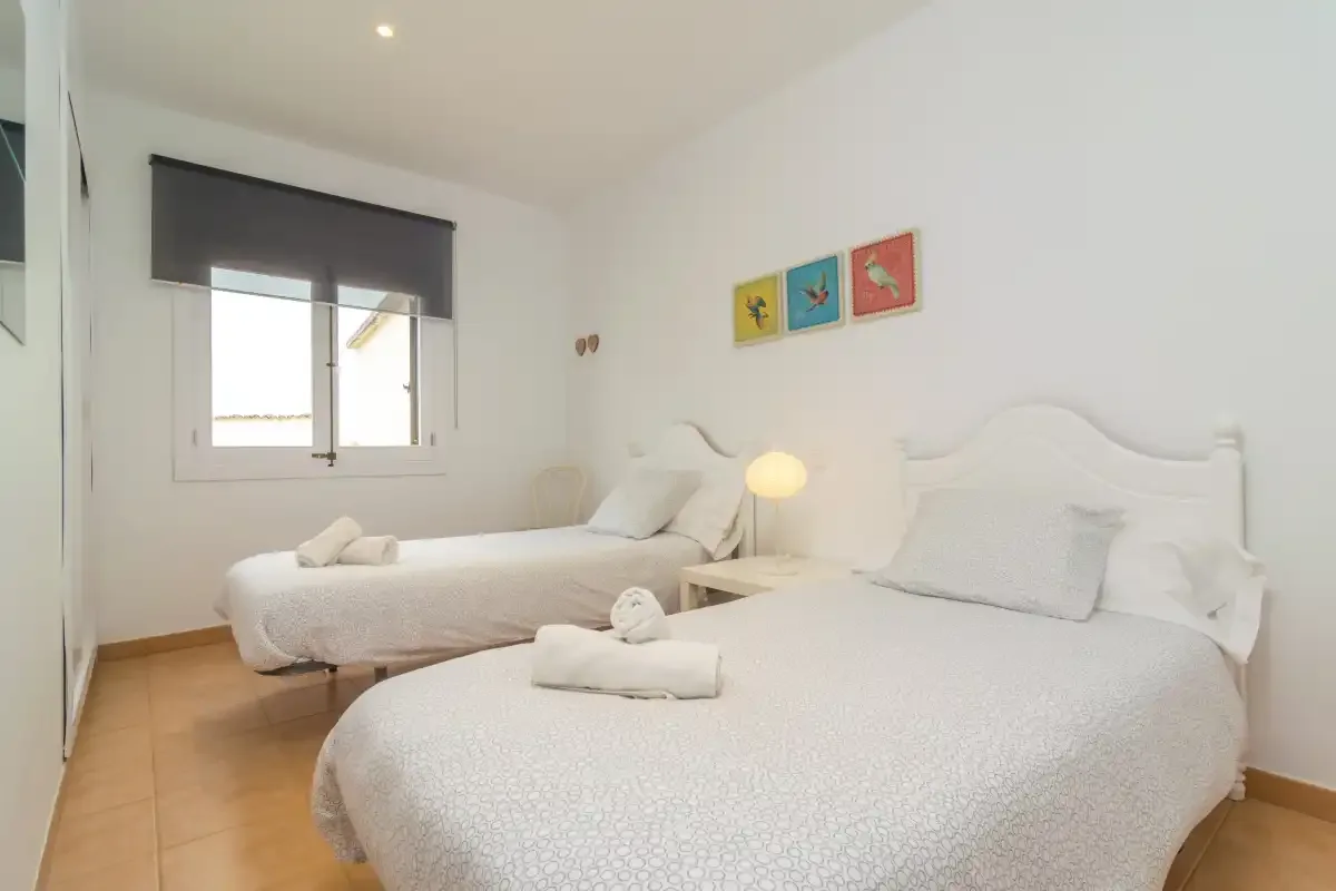 A bright bedroom with two beds, white bedding, and colorful artwork on the wall.