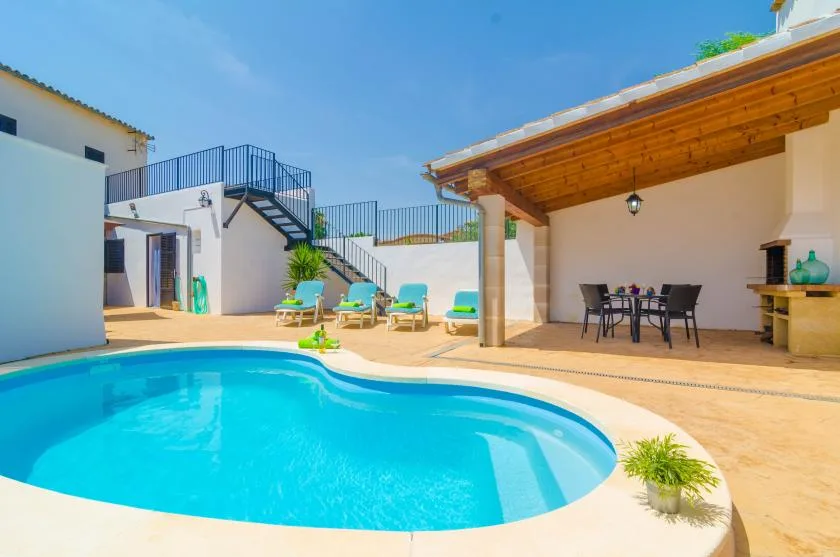 Una piscina al aire libre junto a un patio cubierto con zona de comedor.