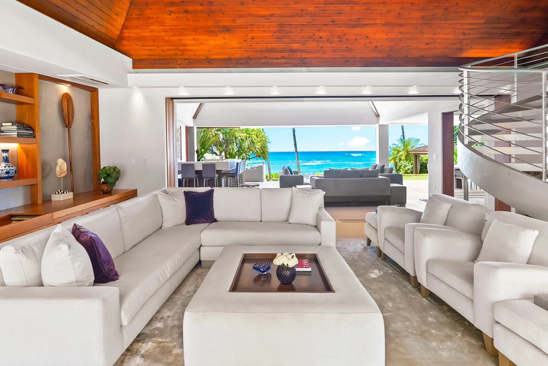 A bright living room with white seating and a view of the ocean.
