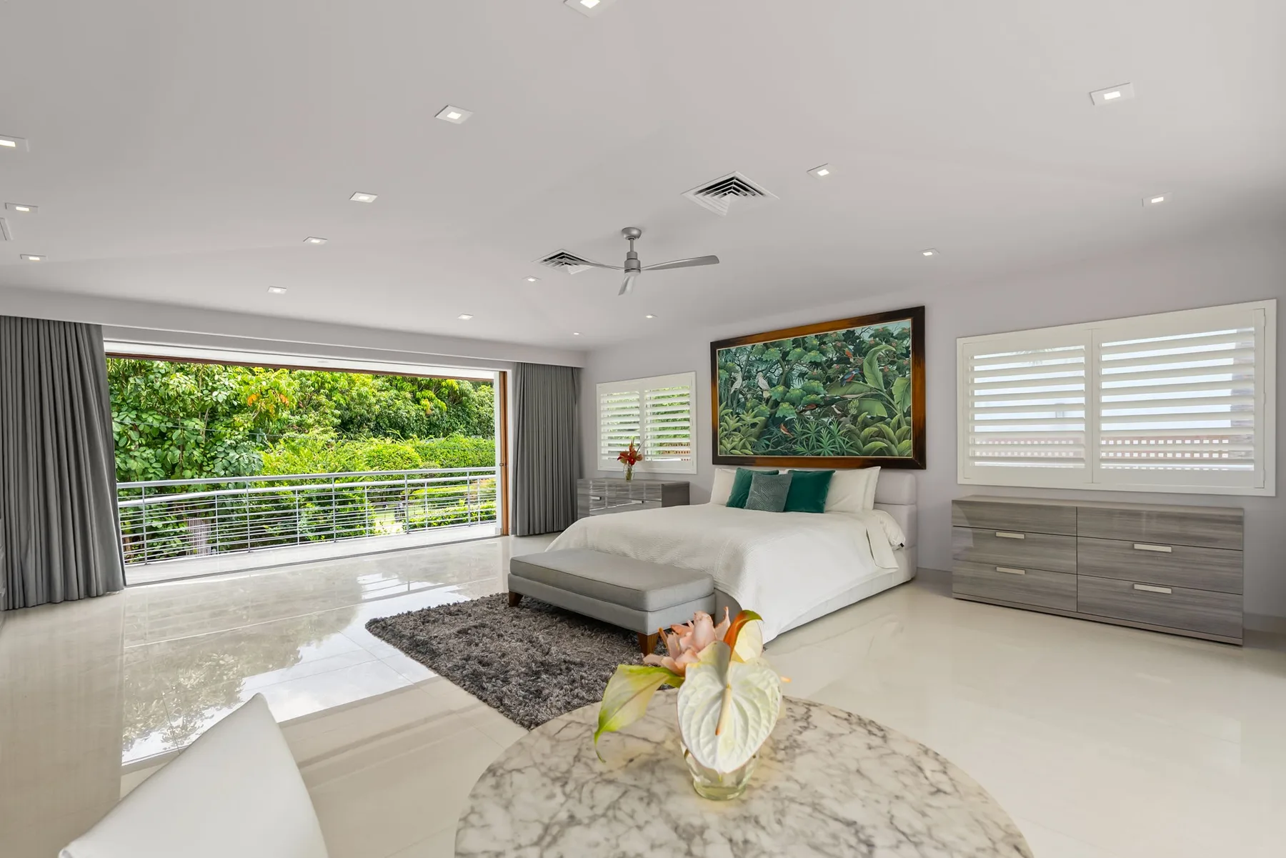 A bright bedroom with a bed, large windows, and a view of greenery.