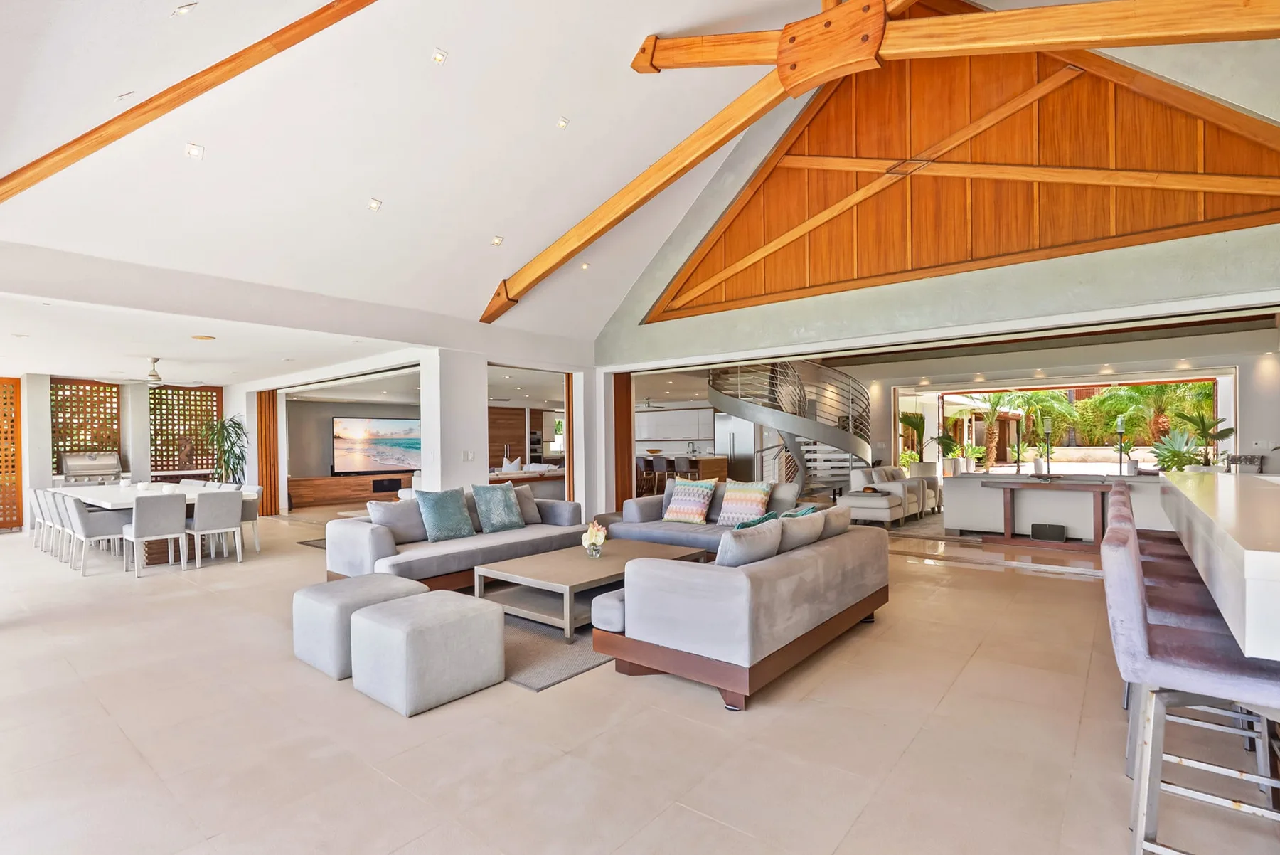 An open-plan living and dining area with seating beneath a high timber ceiling.
