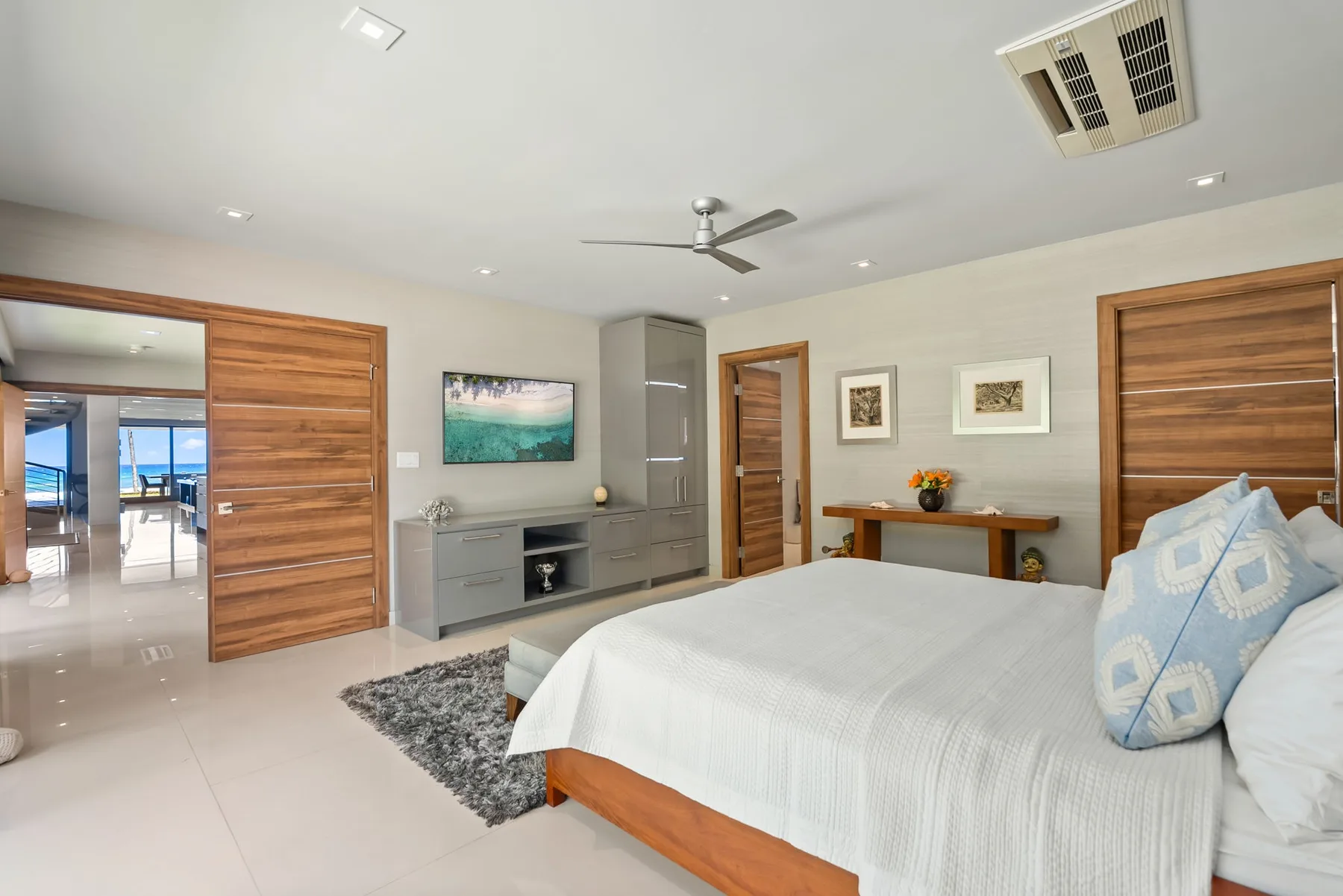 A bright bedroom with a large bed, a wooden desk, and built-in storage.