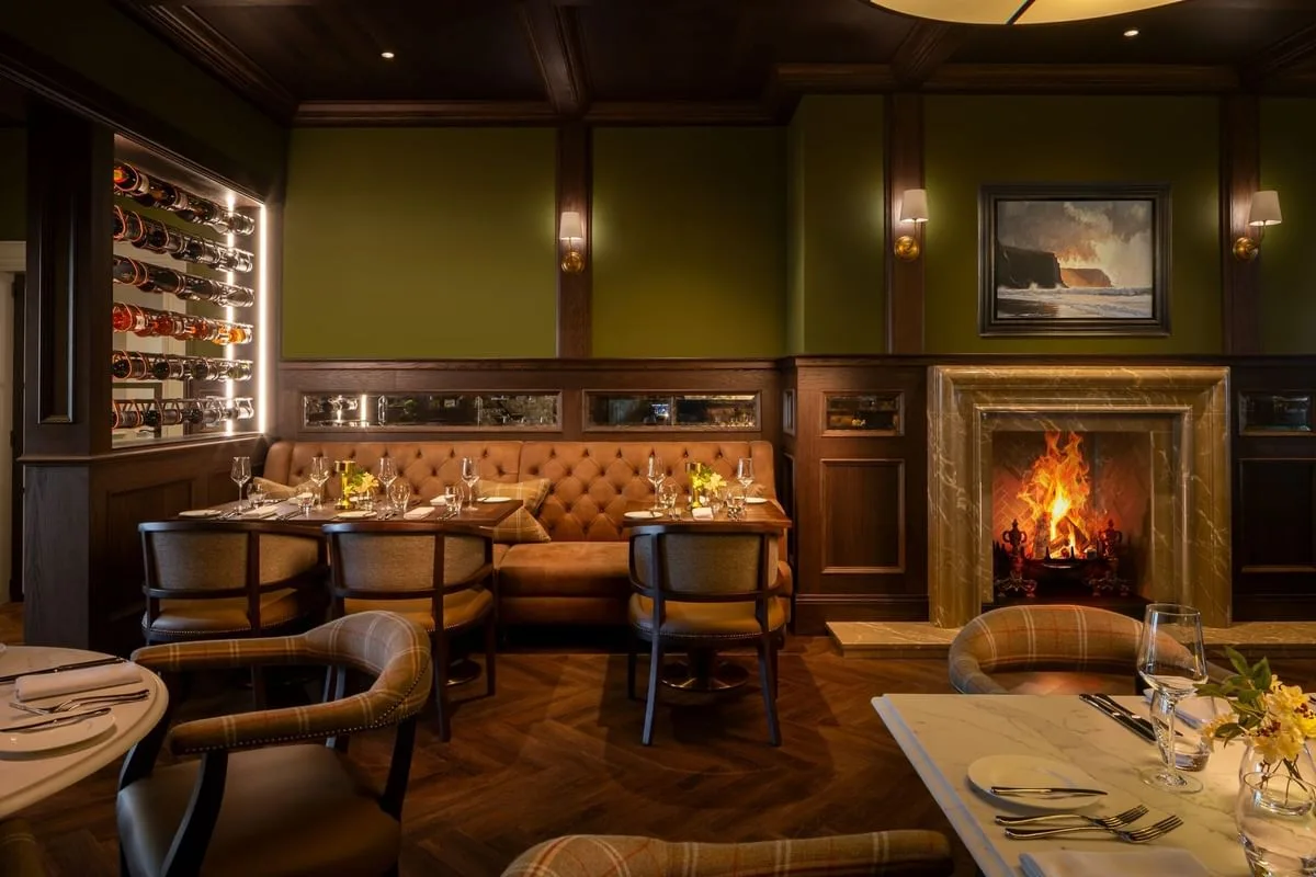Zona de mesas del restaurante junto a la chimenea y el botellero