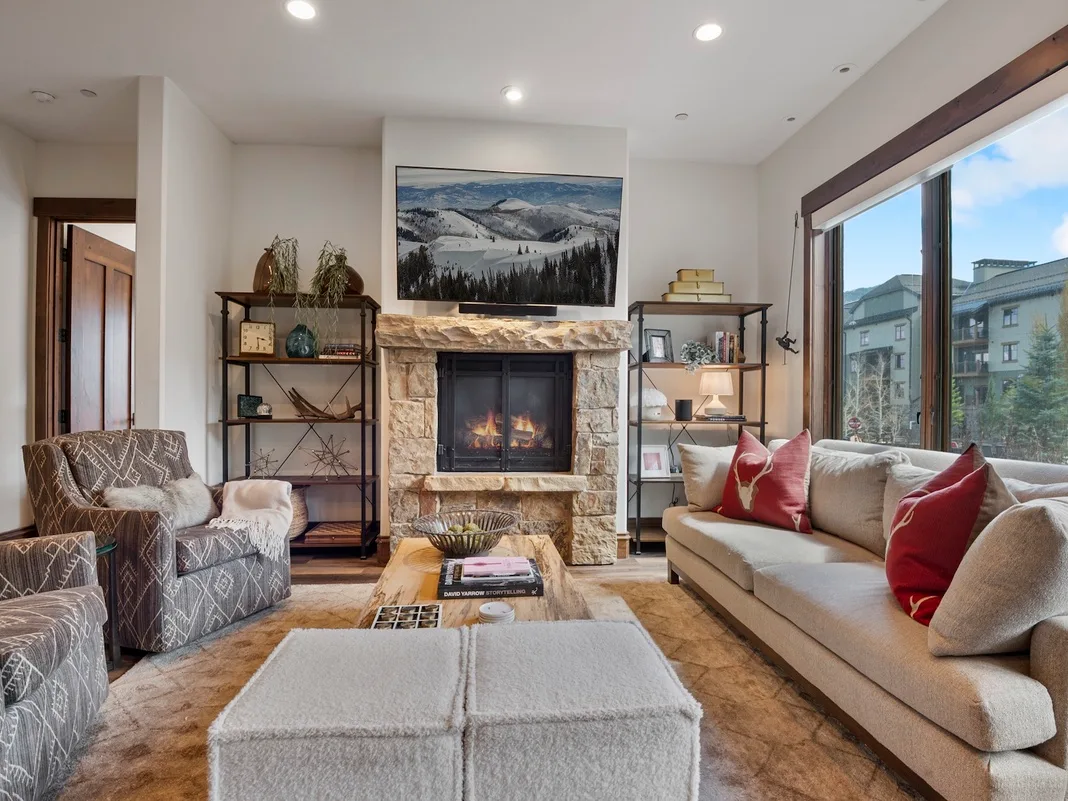 A living room with a fireplace and seating beside large windows.