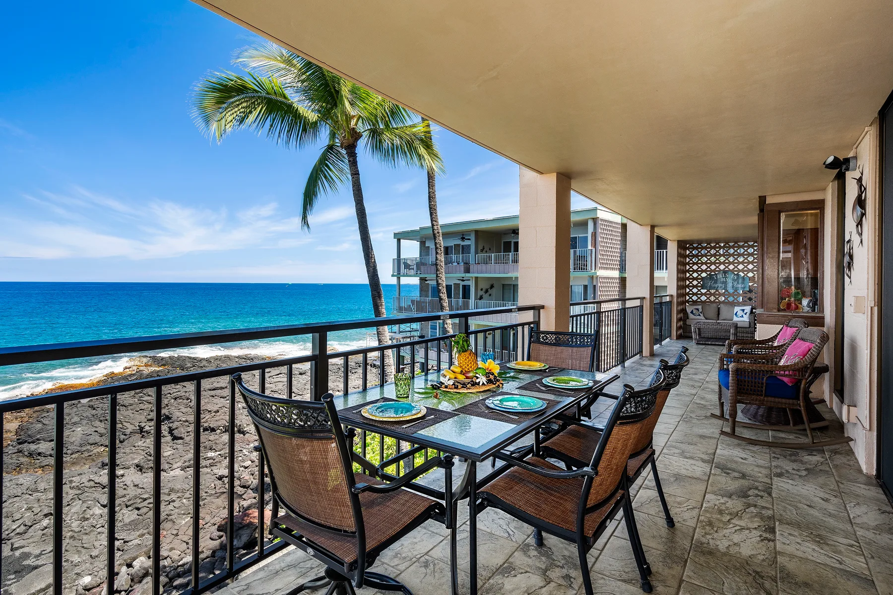 Una terraza cubierta frente al mar con una mesa de comedor y asientos con vista al agua.