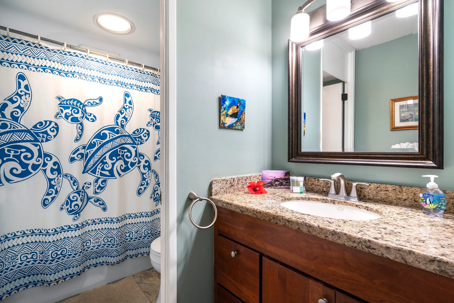 Un baño con una cortina de ducha estampada y un tocador con espejo.