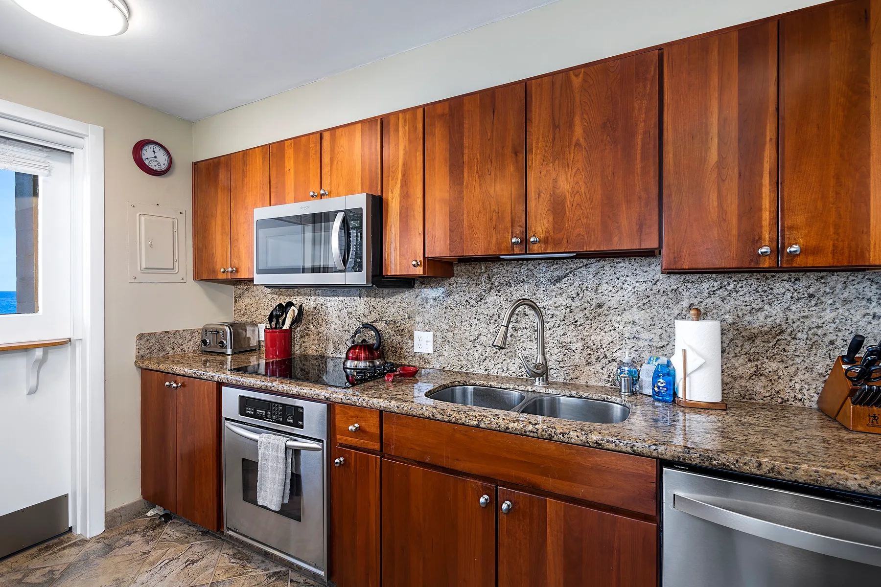 Una cocina con gabinetes de madera, un microondas y una encimera larga.