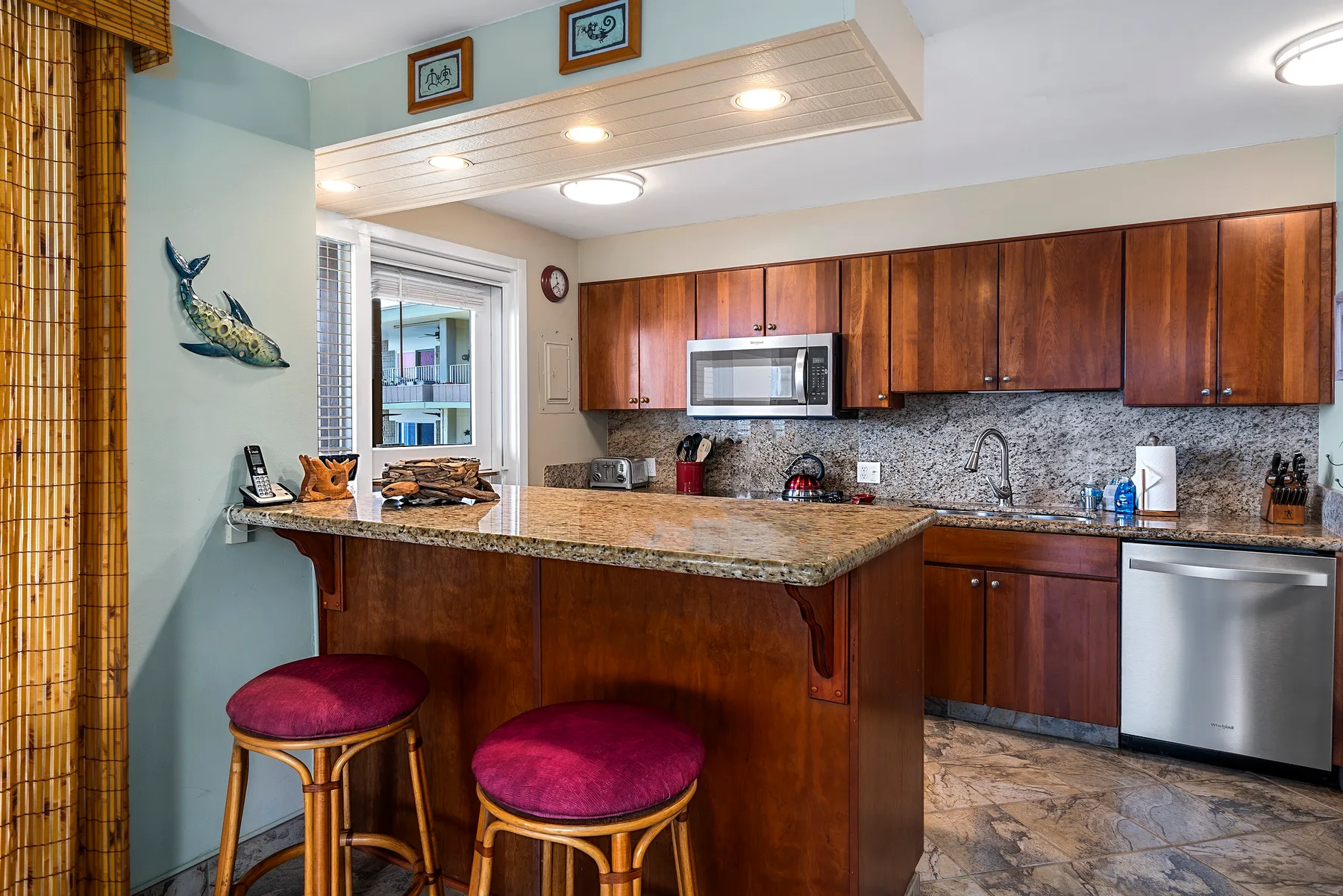 Una cocina con barra, gabinetes de madera y dos taburetes.