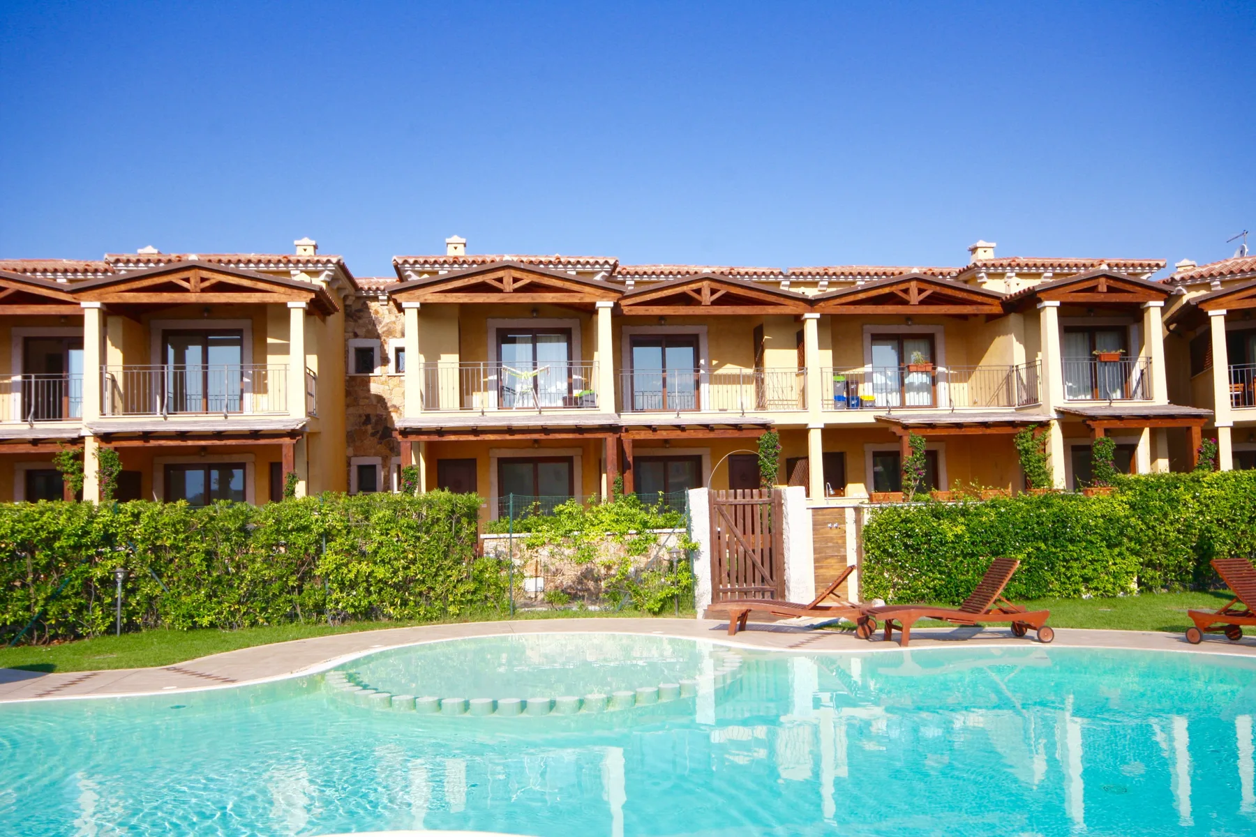 Una piscina frente a una fila de casas de dos plantas con balcones.