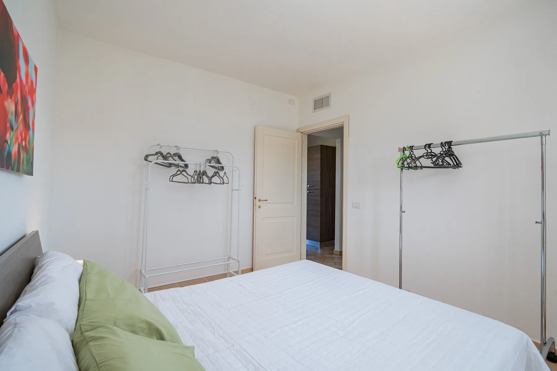 Un dormitorio con una cama y dos percheros abiertos.
