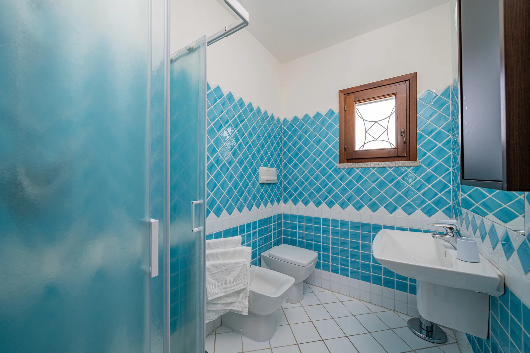 Un baño con azulejos, ducha, inodoro y lavabo.
