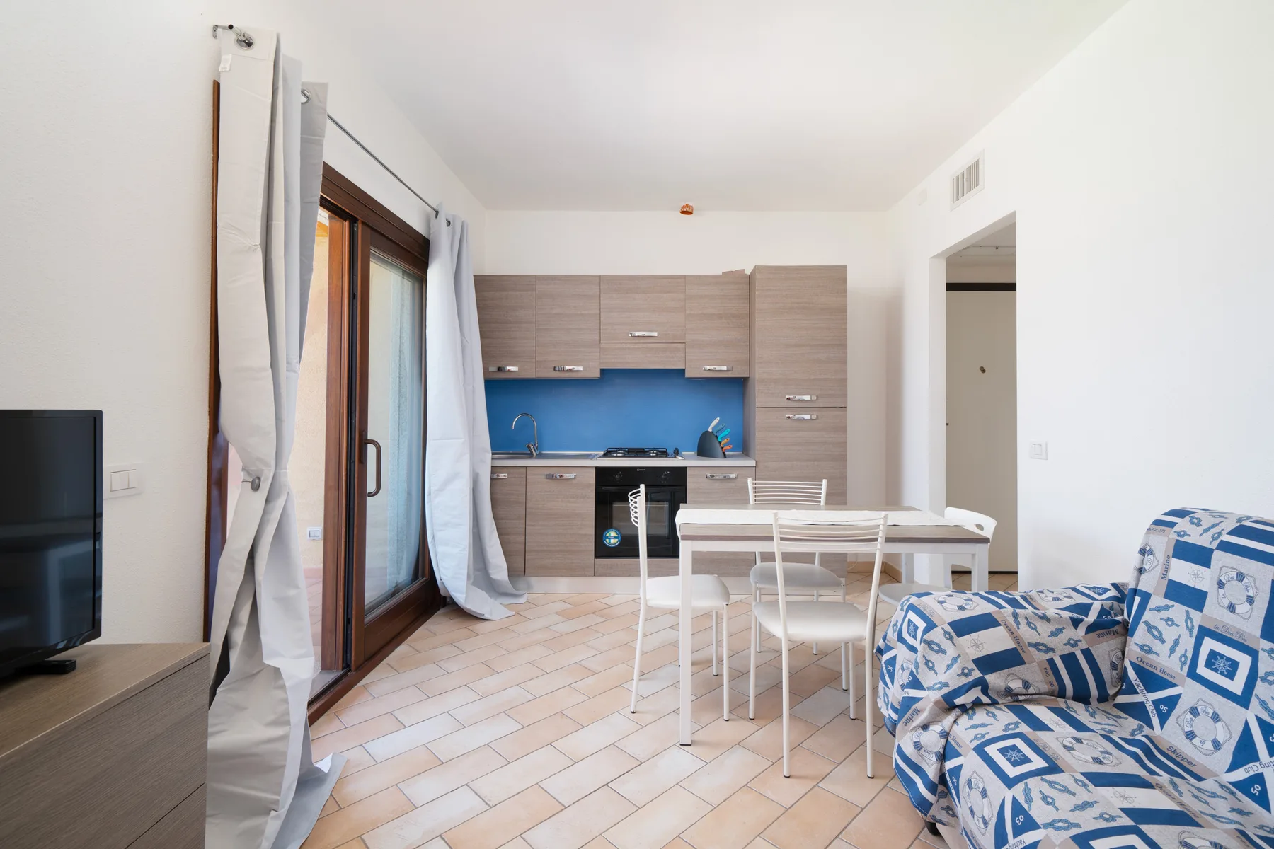 Una luminosa sala de estar diáfana con cocina compacta, mesa de comedor y asientos estampados.