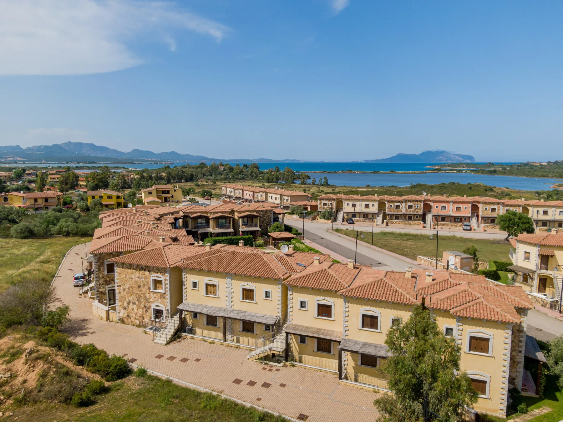 Un conjunto residencial costero con hileras de casas y el mar al fondo.