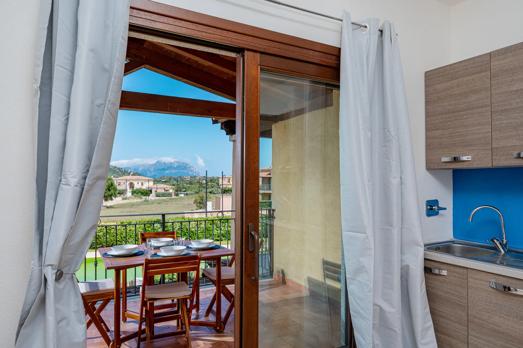Un comedor da a un balcón con asientos al aire libre y vistas a las montañas.