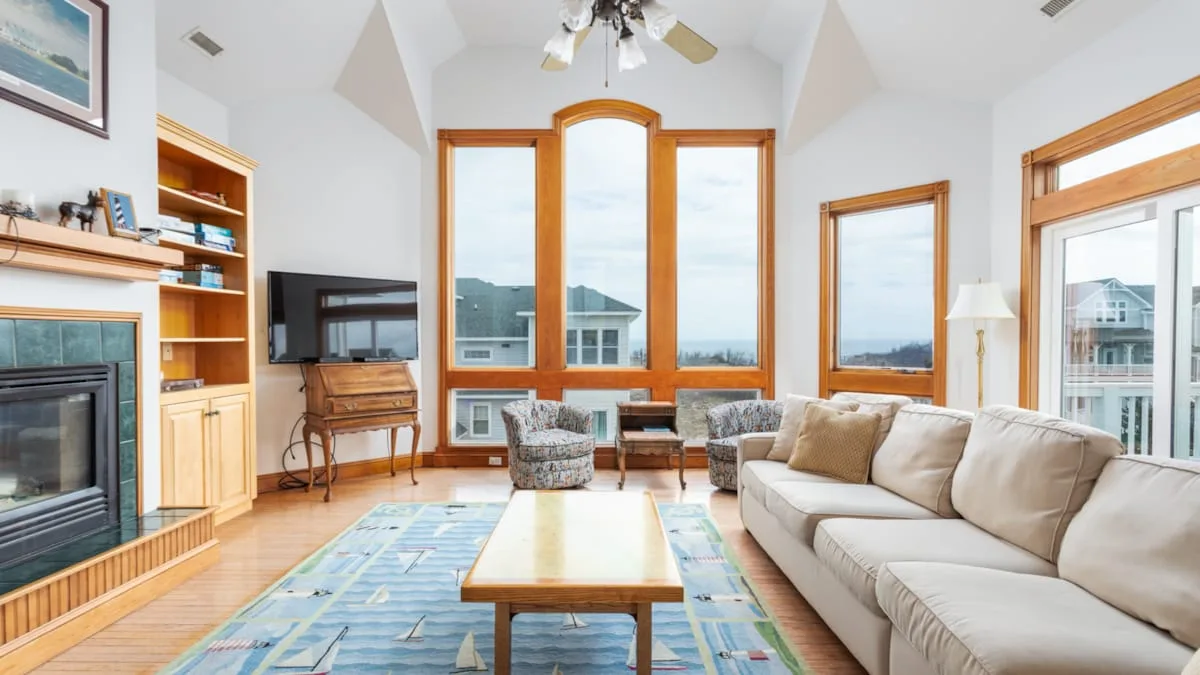 Una luminosa sala de estar con asientos alrededor de una mesa de centro junto a grandes ventanas.
