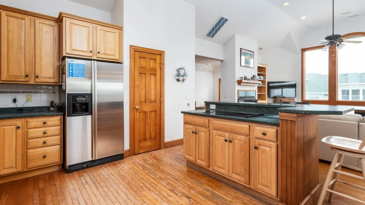 Una cocina con gabinetes de madera, electrodomésticos de acero inoxidable y una isla central.