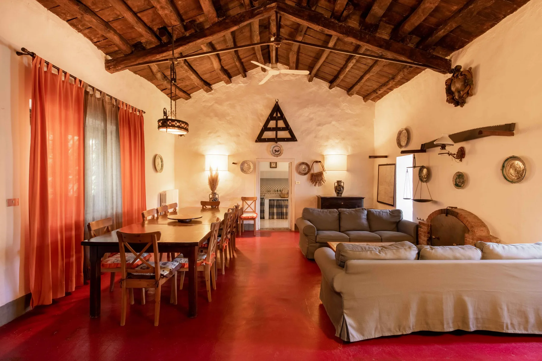 Una sala rústica con comedor, asientos, una mesa y suelo rojo.