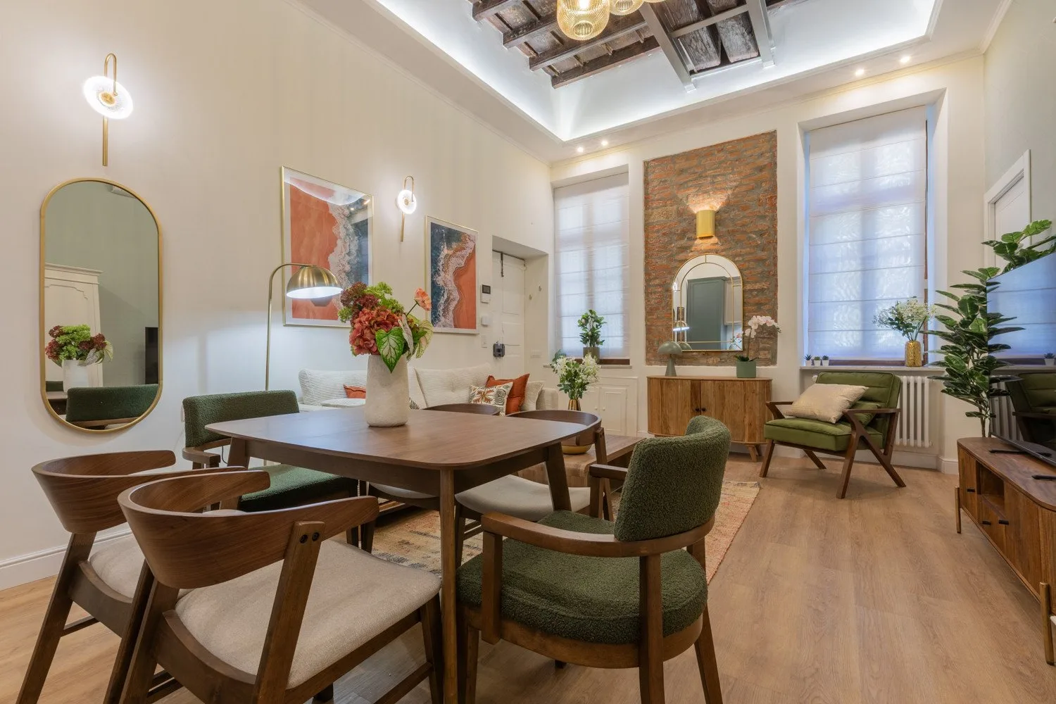 A dining and sitting area with a wooden table, upholstered seating, and a brick accent wall.