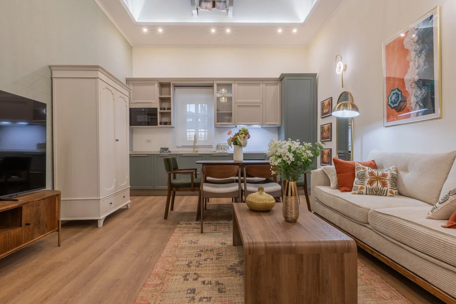 Sala de estar y comedor con un sofá, una mesa de madera y la cocina al fondo.