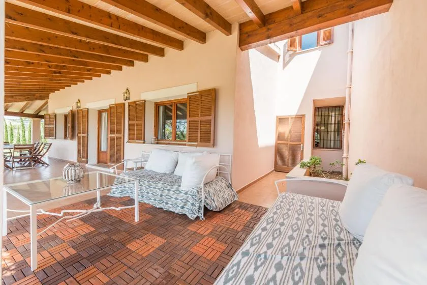 Un patio cubierto con asientos estampados y techo de vigas de madera.