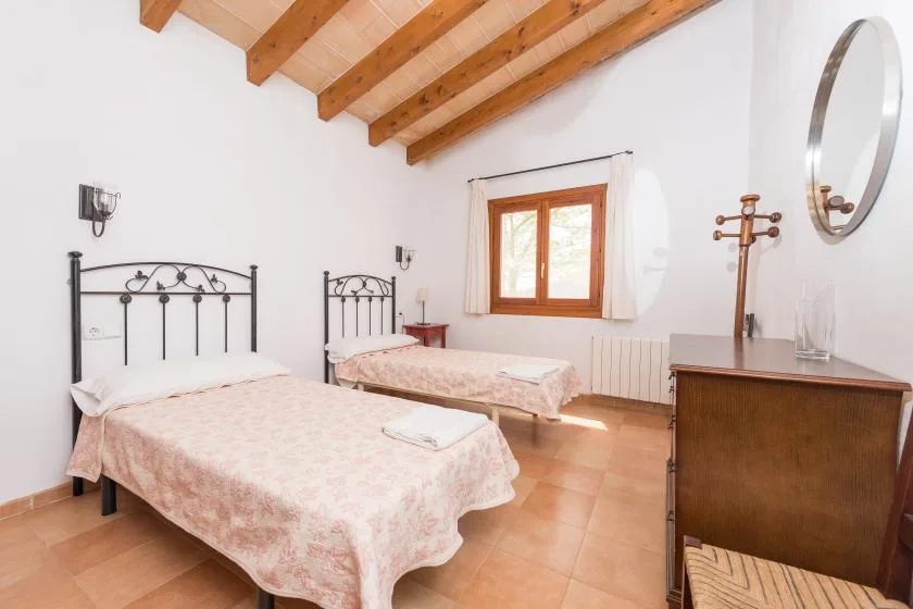 Un dormitorio con dos camas, techo de madera y una ventana.