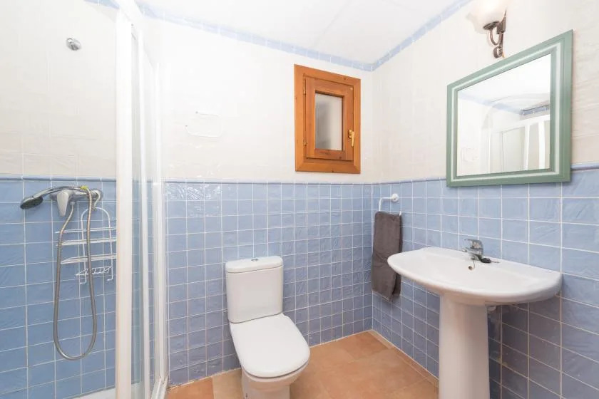 Un baño con azulejos, ducha, inodoro y lavabo.