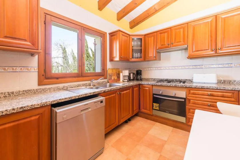 Una cocina con gabinetes de madera, encimeras de granito y una ventana.