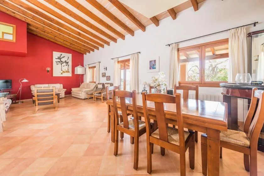 Un comedor y sala de estar con una mesa de madera, asientos y una pared roja.