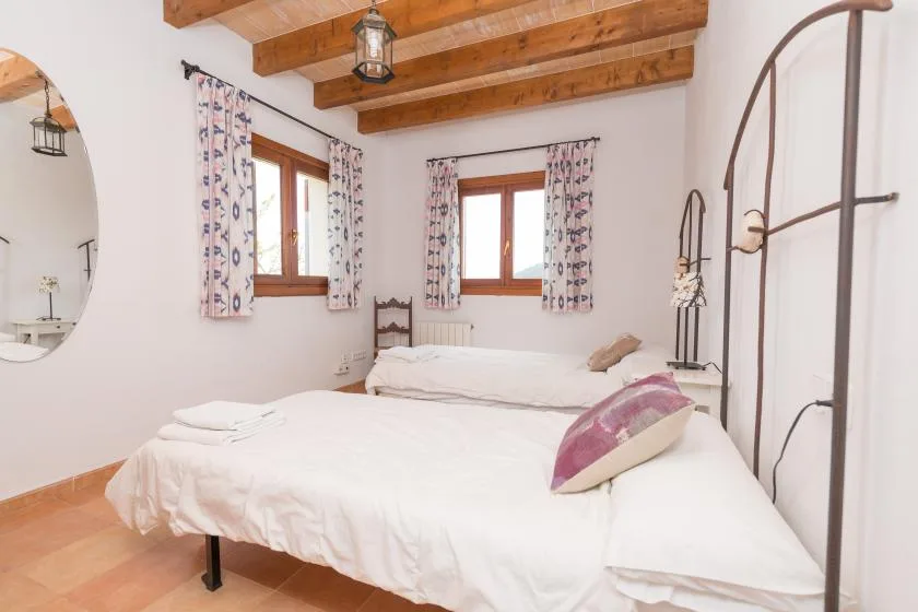Un dormitorio con una cama grande bajo vigas de madera a la vista.